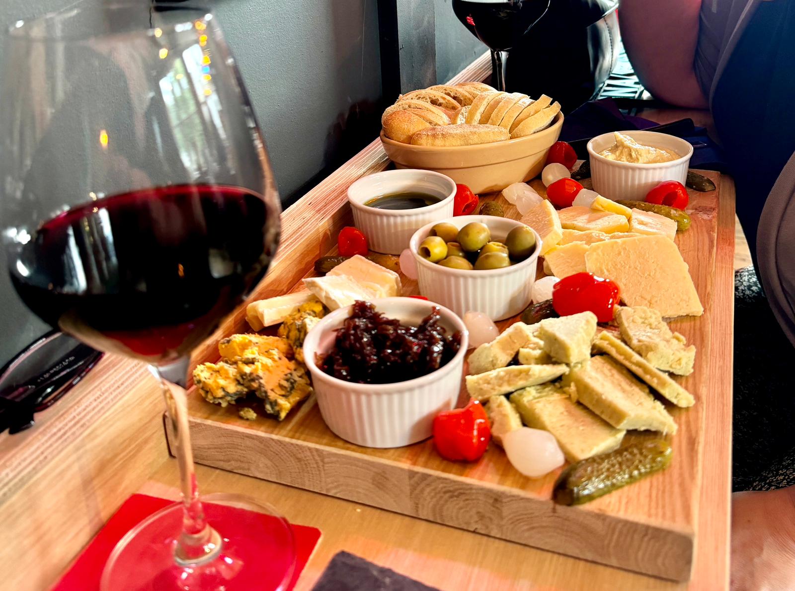 A generous cheese board with bread, olives, chutney and red wine